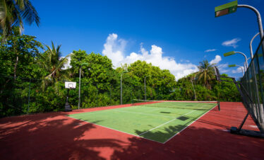 Tennis court surrounded by lush tropical greenery at Ayada Maldives under a bright blue sky