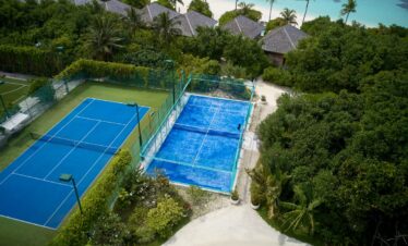 Tennis courts surrounded by lush greenery at Hurawalhi Island Resort