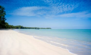 The Sarojin Khao Lak pristine beach with soft white sand and turquoise waters stretching into the horizon