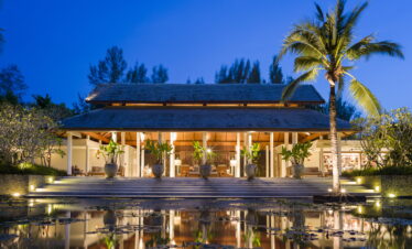 The Sarojin Khao Lak resort lobby at night with reflecting pond and tropical plants in front
