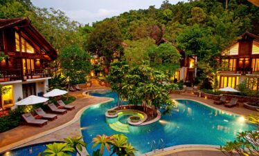 The Tubkaak Krabi pool with surrounding villas and lush trees in the evening