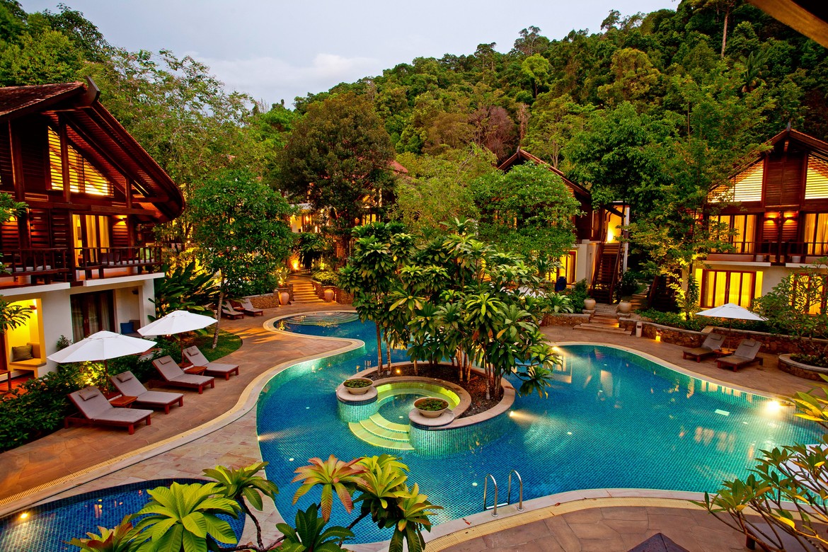 The Tubkaak Krabi pool with surrounding villas and lush trees in the evening