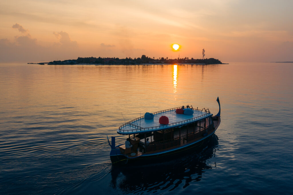 Traditional boat on calm waters at sunset Adaaran Meedhupparu in the background