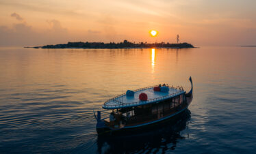 Traditional boat on calm waters at sunset Adaaran Meedhupparu in the background