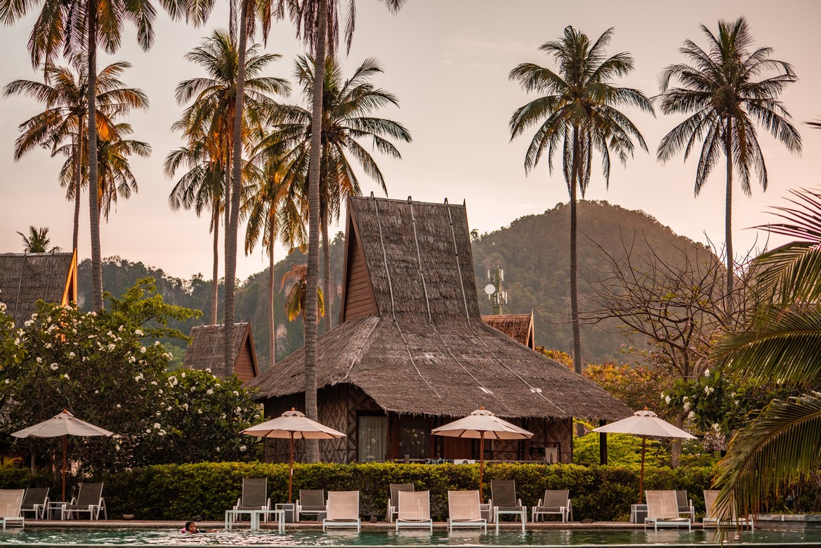 Traditional huts and palm trees at sunset at Saii Phi Phi Island Village