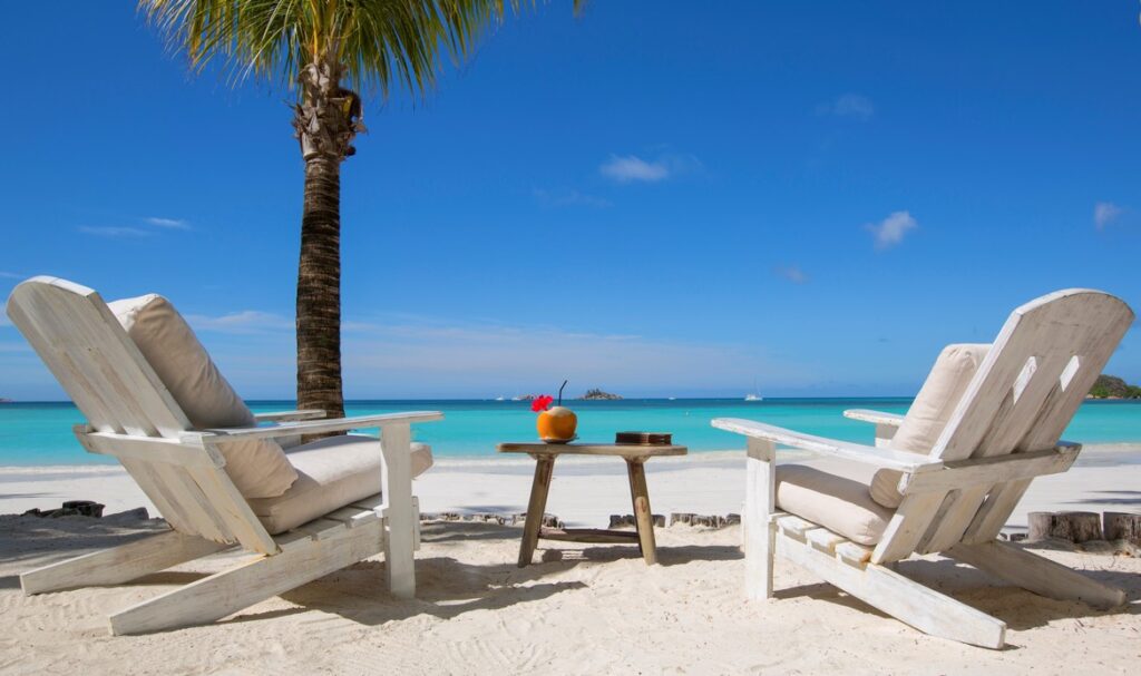 Two beach chairs facing the ocean with a drink table at Paradise Sun