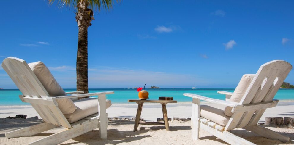 Two beach chairs facing the ocean with a drink table at Paradise Sun