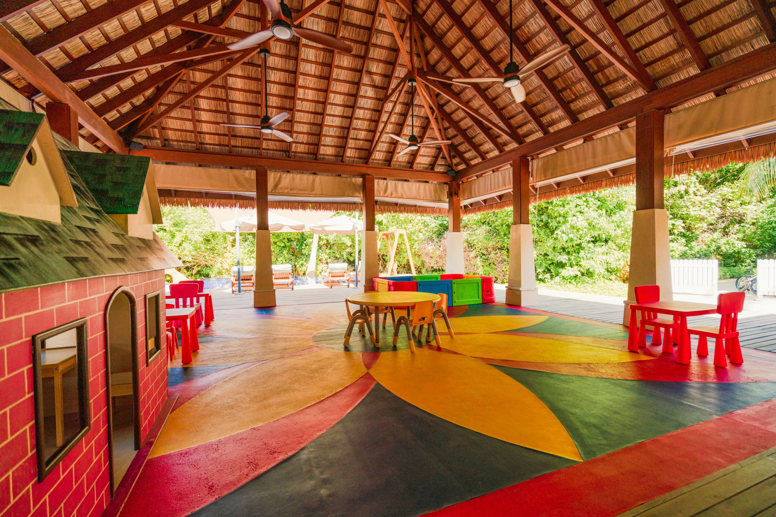 Vibrant kids play area at Ayada Maldives with colorful tables chairs and a thatched roof