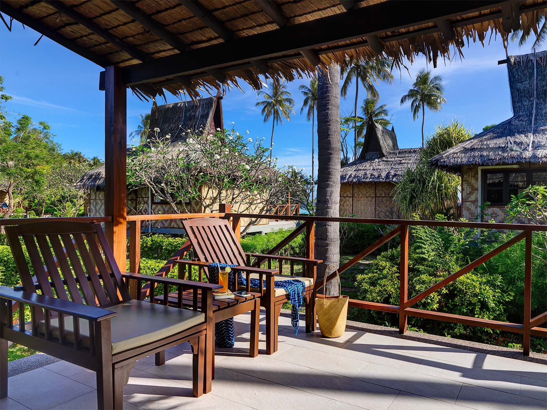 Wooden chairs on a porch with garden view at Saii Phi Phi Island Village