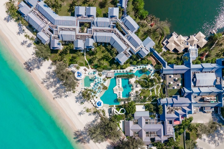 Aerial view of Saii Laguna resort beachside with pools and lush greenery
