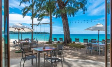 Beachfront dining setup at Saii Laguna under umbrellas with swings and sea view