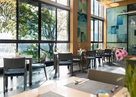 Bright dining area at Amari Phuket with large windows and greenery outside