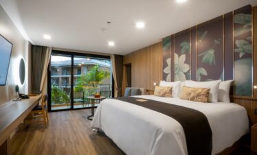 Comfortable king sized bed in a stylish room with a balcony view at La Flora Khao Lak