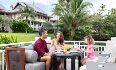 Family enjoying breakfast on Saii Laguna terrace surrounded by tropical gardens