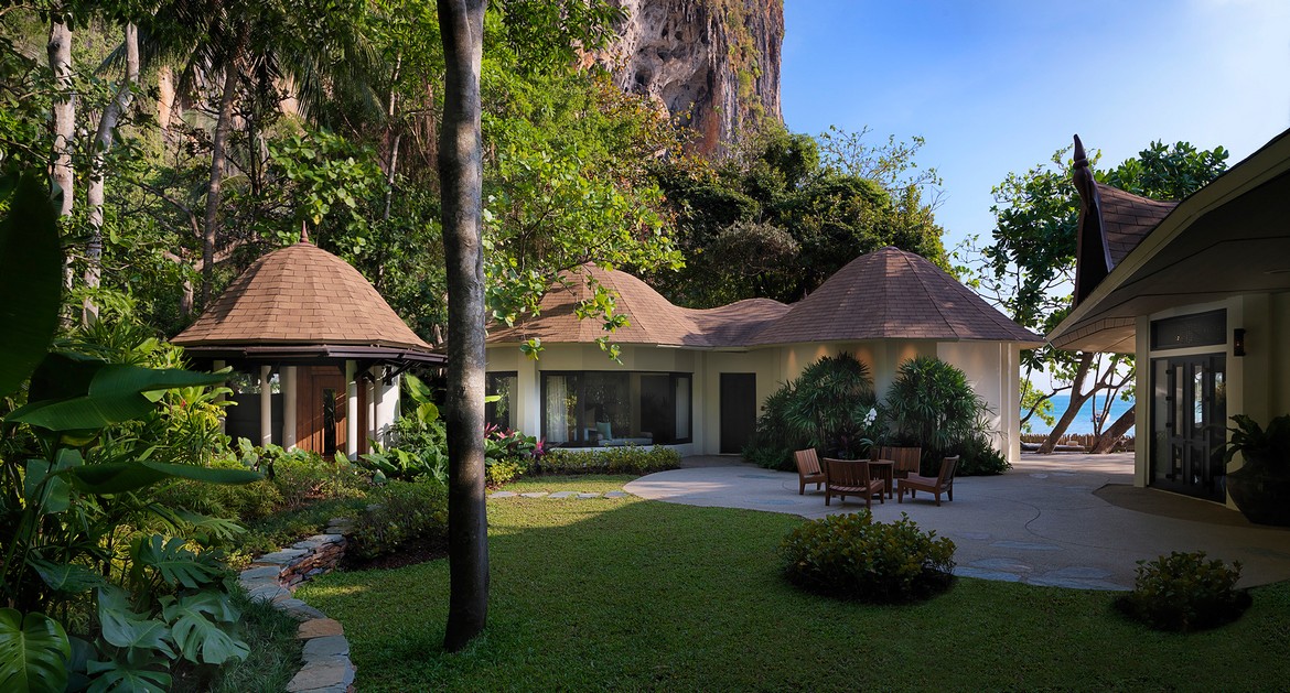 Garden view of Rayavadee Krabi villa with thatched roofs nestled among lush tropical greenery