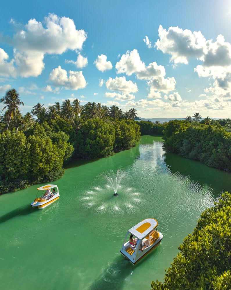 Kandima paddle boats on lush mangrove canal with fountain