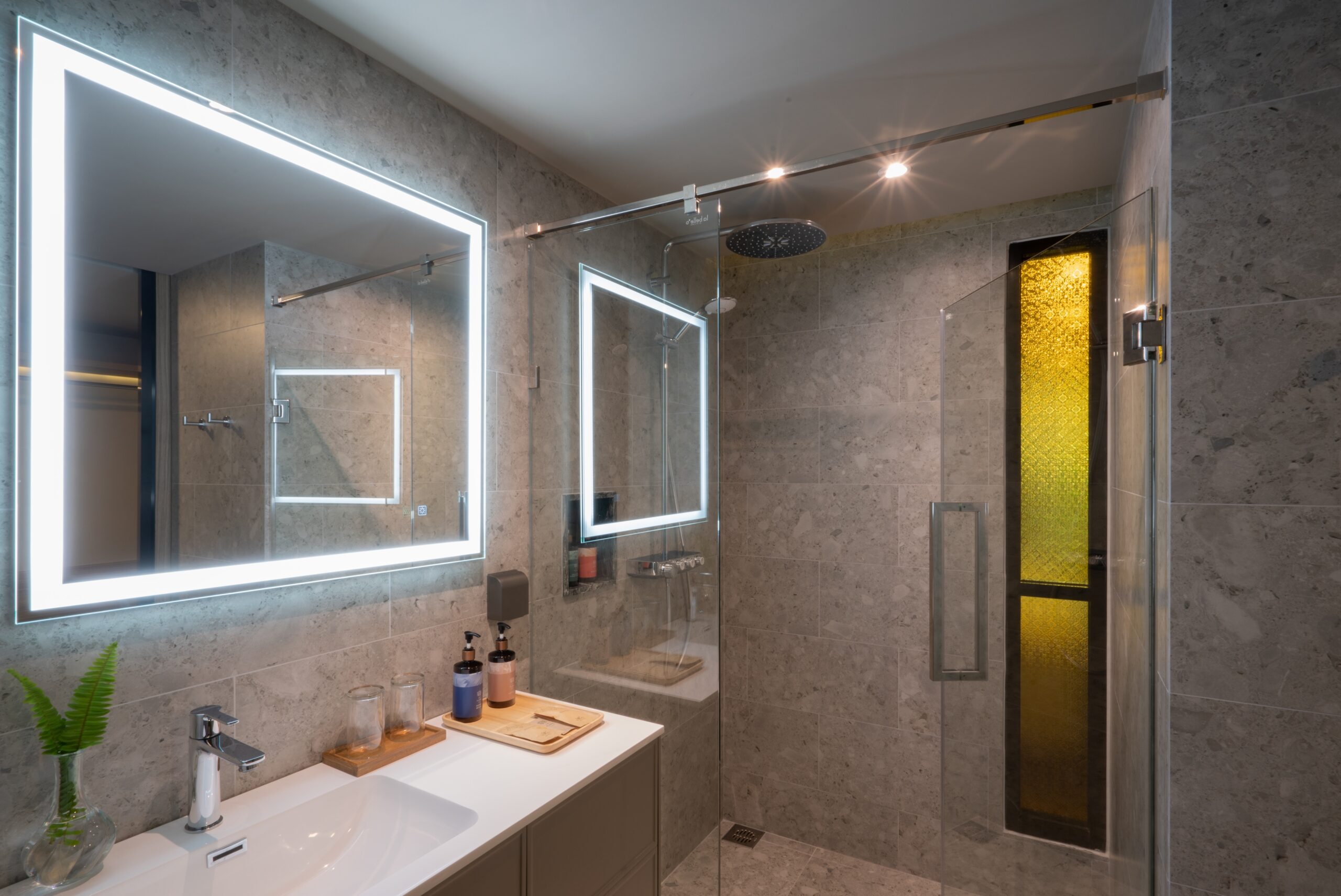 Modern bathroom with illuminated mirror and glass shower enclosure at La Flora Khao Lak