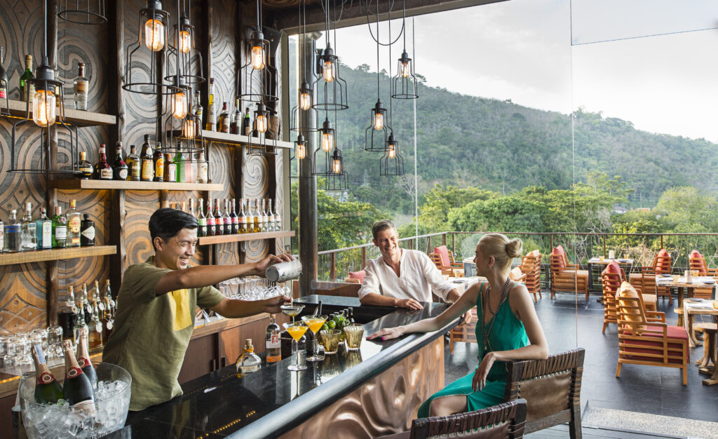 Outdoor bar area with patrons enjoying drinks and scenic views at Keemala