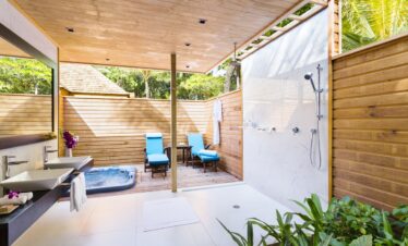 Outdoor bathroom with jacuzzi and loungers at Veligandu