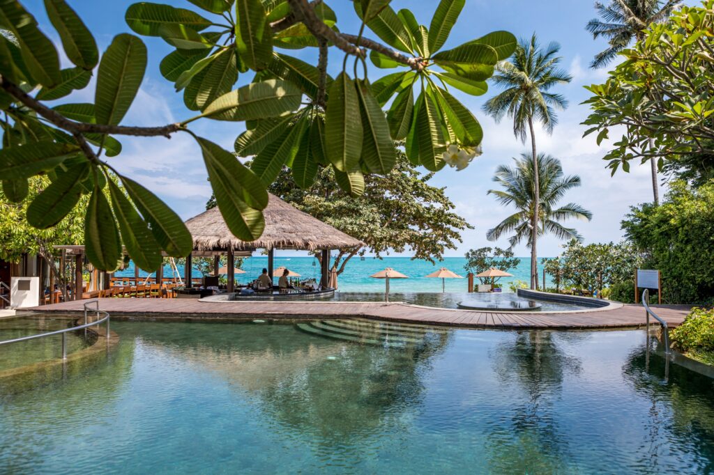 Outdoor pool at Saii Koh Samui surrounded by lush greenery and a view of the turquoise ocean