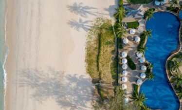 Overhead view of Katathani pool and sandy beachfront lined with loungers