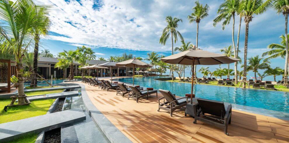 Relaxing pool area with sun loungers under palm trees at La Flora Khao Lak