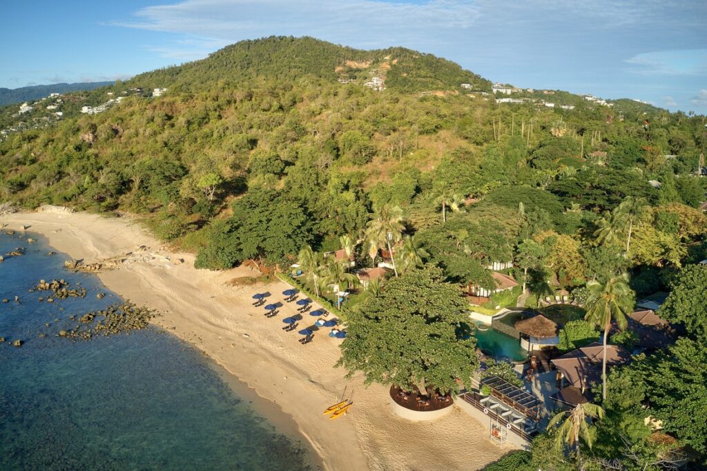 Saii Koh Samui resort set along a serene beach with lush green hills in the background