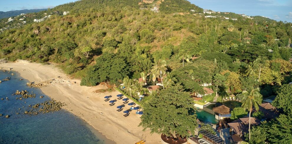 Saii Koh Samui resort set along a serene beach with lush green hills in the background