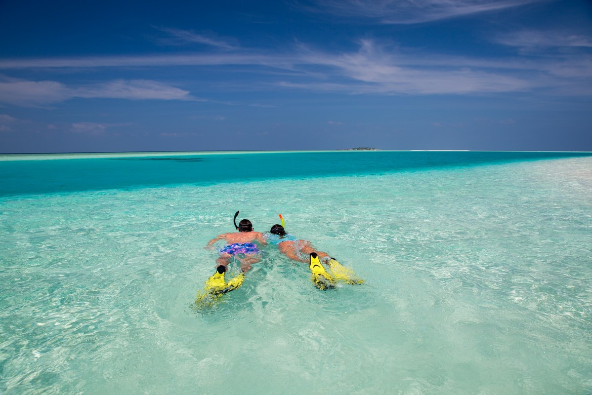 Snorkeling in turquoise waters near Veligandu island beaches
