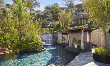 Tranquil pool area with a cascading waterfall surrounded by greenery at Keemala