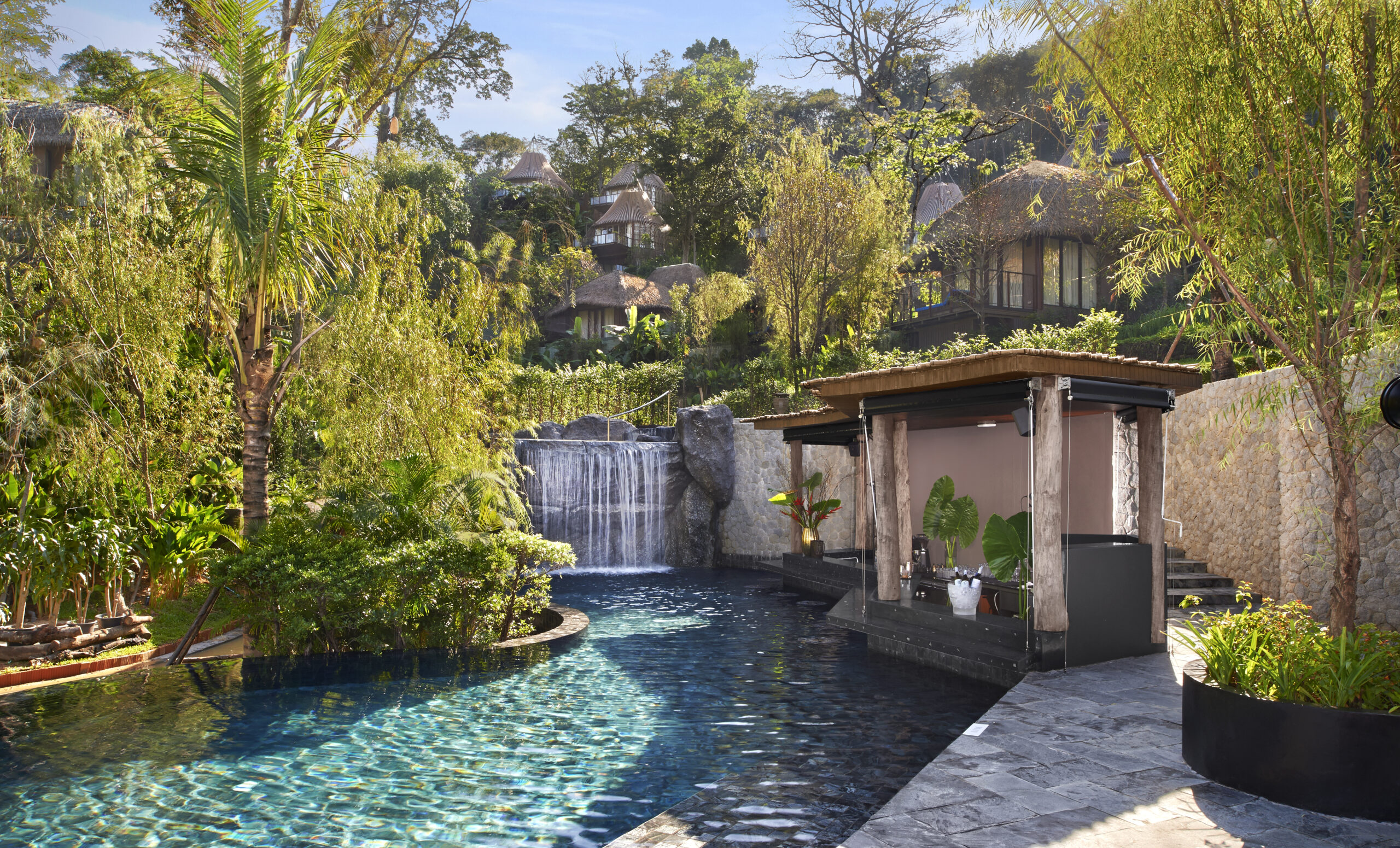 Tranquil pool area with a cascading waterfall surrounded by greenery at Keemala