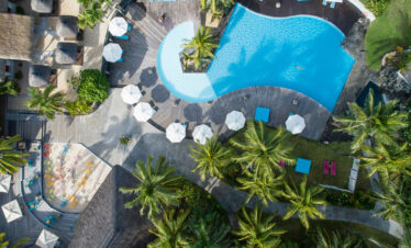 Aerial view of Solana Beach pool area with sunbeds umbrellas and tropical greenery