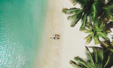 Aerial view of the pristine beach at Paradise Cove Boutique with palm trees