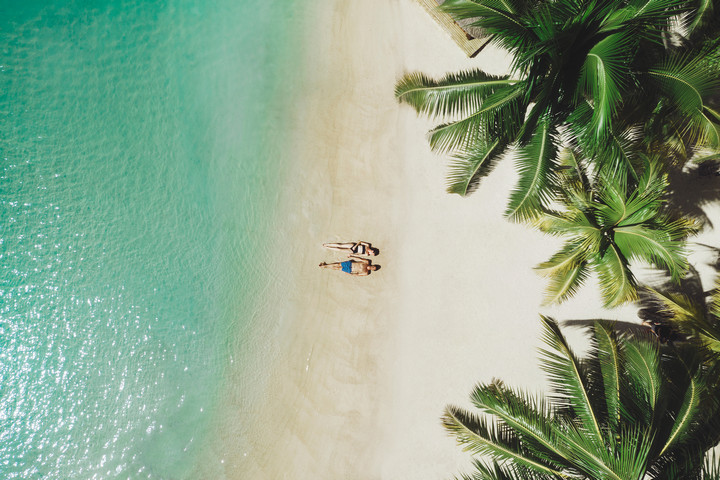 Aerial view of the pristine beach at Paradise Cove Boutique with palm trees
