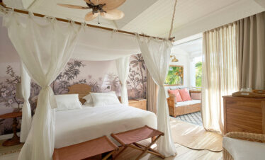 Elegant bedroom with a canopy bed and tropical design at Paradise Cove Boutique