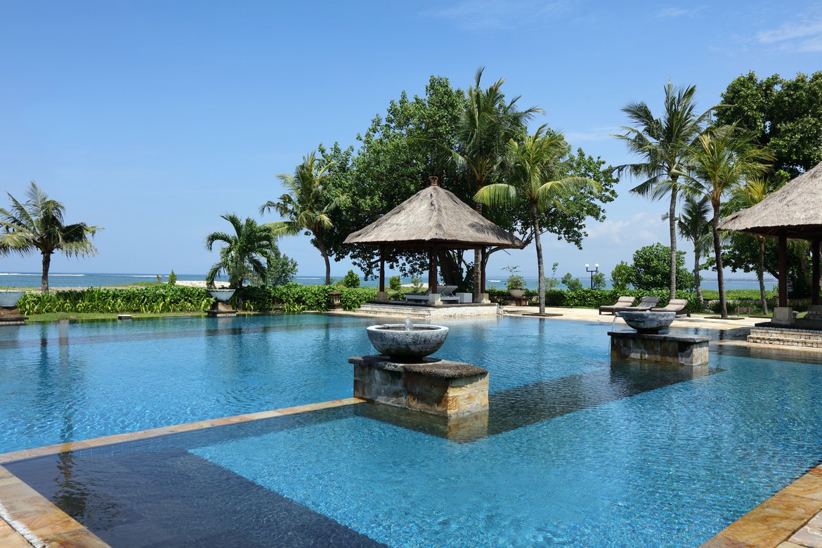 Patra Bali Resort and Villas infinity pool with ocean and palm trees