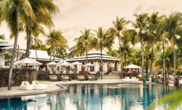Poolside view at Paradise Cove Boutique with palm trees and luxurious seating
