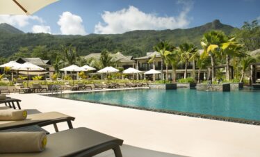 Resort pool area with mountain views palm trees and comfortable loungers Story of serene poolside relaxation