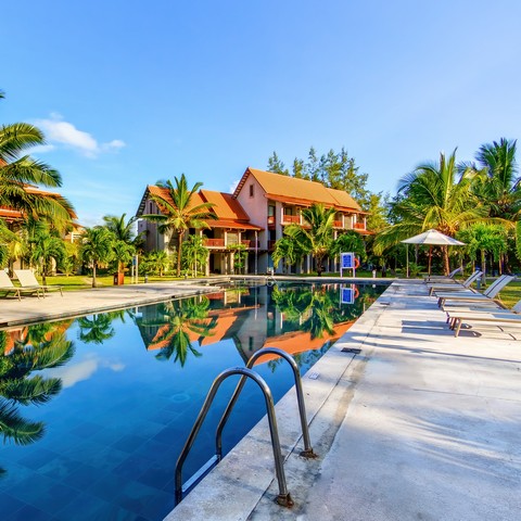 Serene poolside area at Crystals Beach Resort with loungers and vibrant greenery