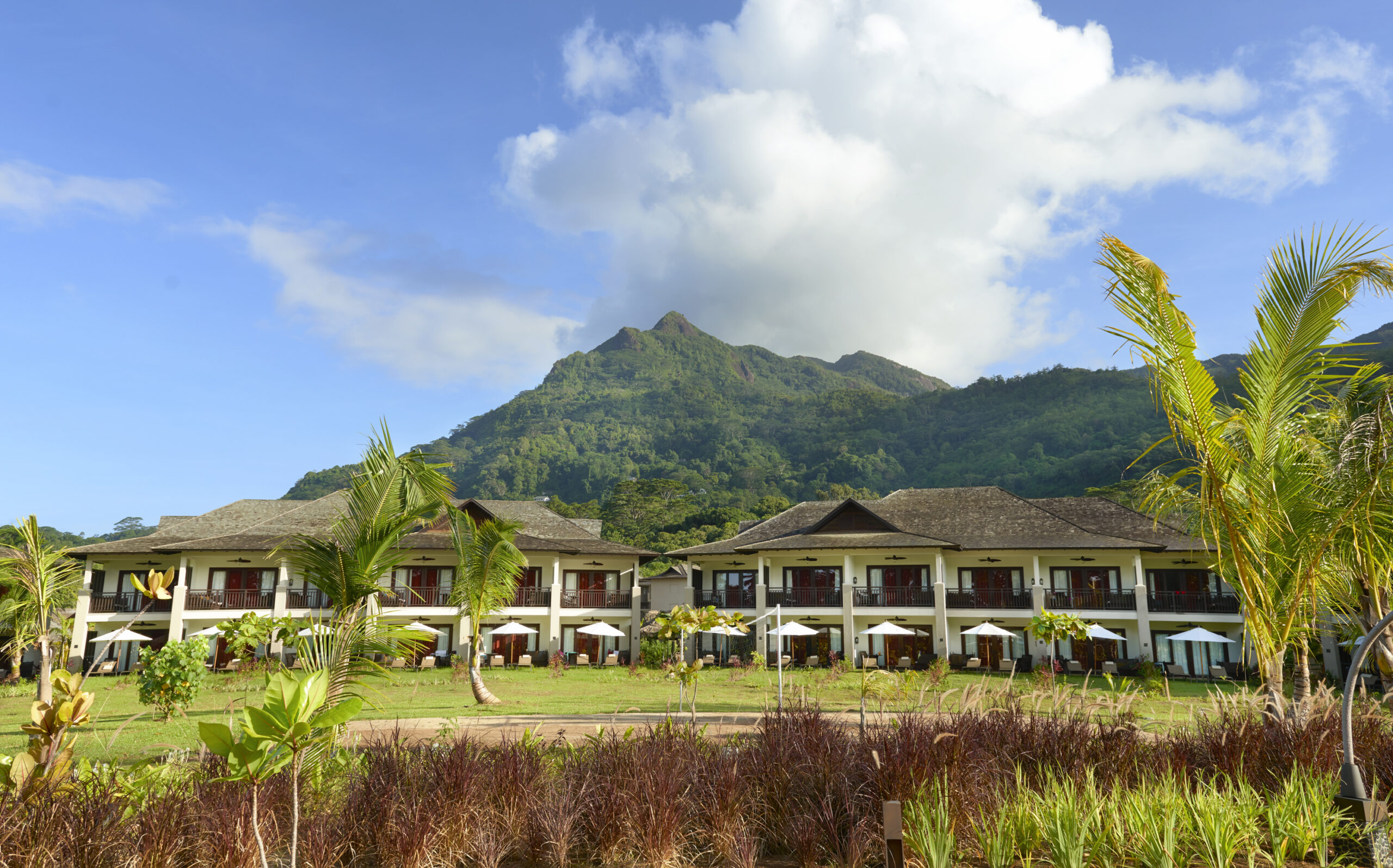 Story of a resort with a stunning mountain backdrop showcasing well-maintained lawns and modern accommodations