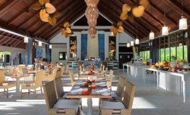 Story of a spacious resort dining area with wicker chairs tropical decor and warm lighting creating a welcoming atmosphere