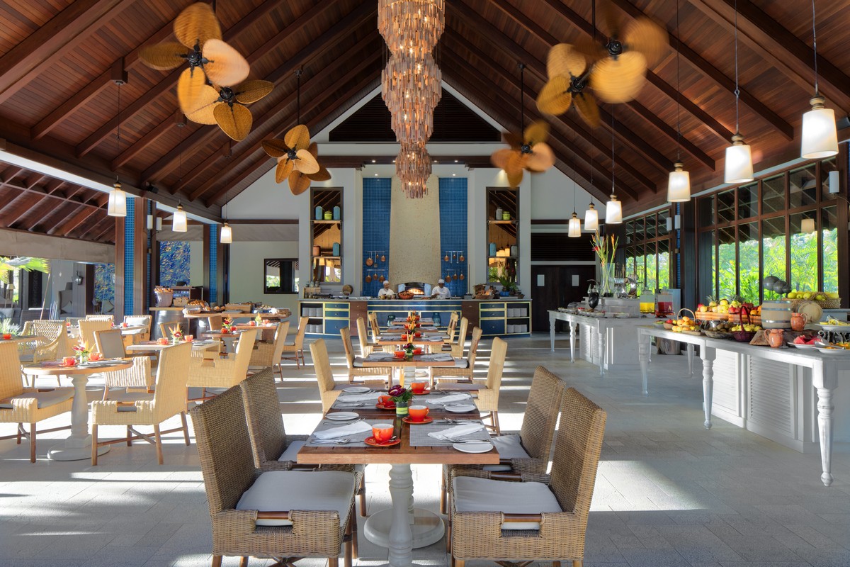 Story of a spacious resort dining area with wicker chairs tropical decor and warm lighting creating a welcoming atmosphere