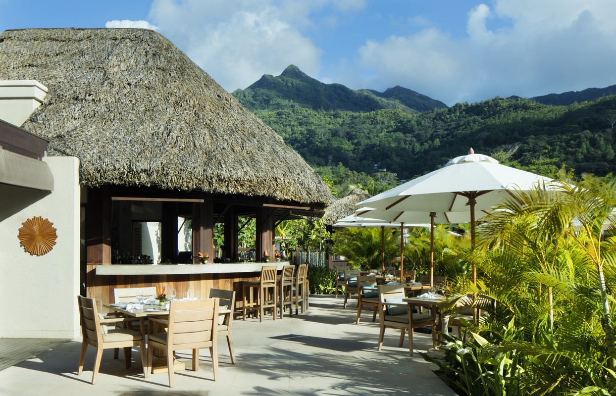 Story of an outdoor dining area at a resort with thatched roofs and mountain views surrounded by greenery