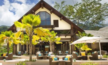 Story of an outdoor lounge area at a resort with comfortable seating under palm trees offering a relaxing tropical setting