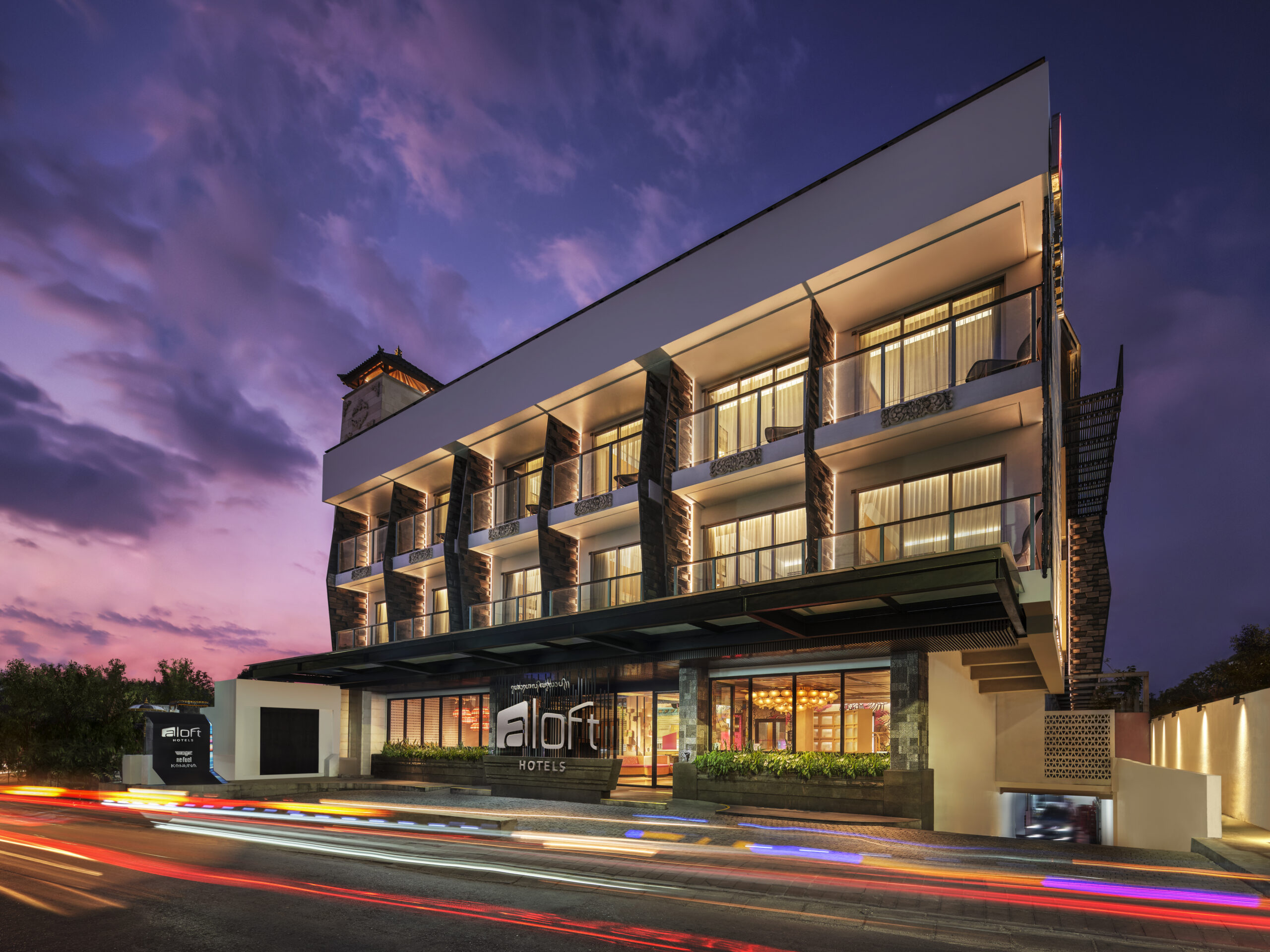 Stylish ALOFT BALI entrance illuminated at sunset with vibrant city lights