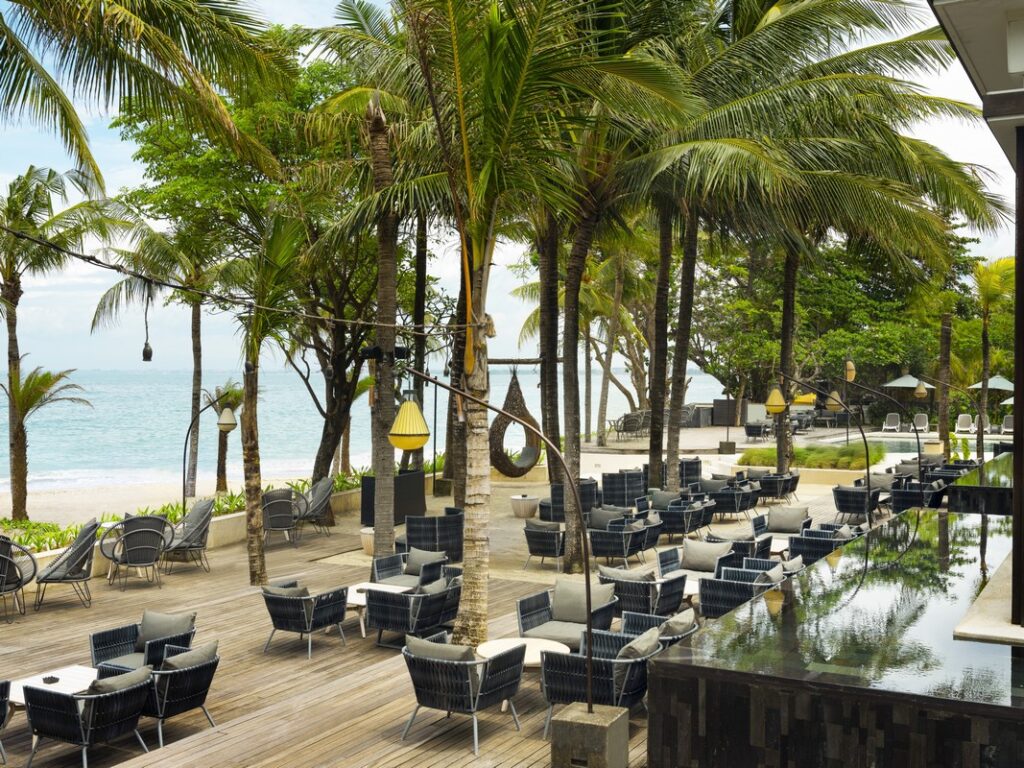 The Anvaya Bali beachfront dining area with palm trees and ocean view