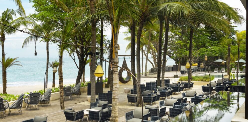 The Anvaya Bali beachfront dining area with palm trees and ocean view