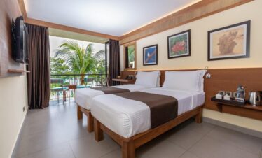 Twin-bed room at Coral Strand Hotel Seychelles with balcony view