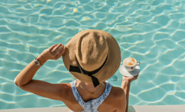 Woman with sun hat enjoying a poolside coffee at Nirvana At Le Meridien Ilse Mauritius under the sun
