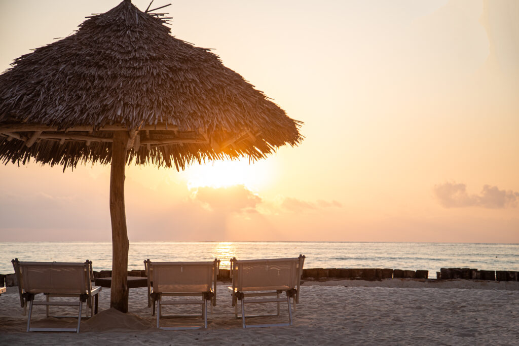Beachfront with straw umbrellas and sun loungers at Tui Blue Bahari overlooking a sunset